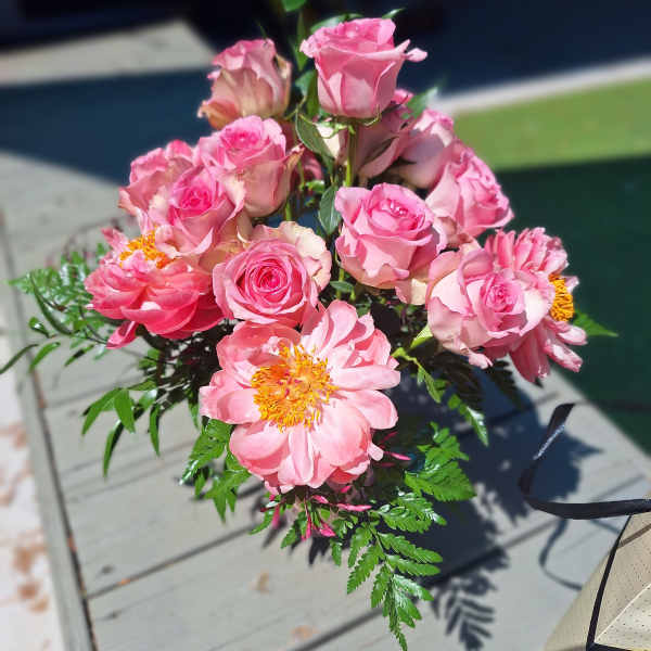 Pink roses and peony-like blooms arranged in a bouquet