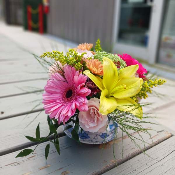 Mixed bouquet in a blue-and-white ceramic bowl with pink and yellow blooms