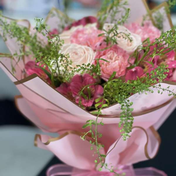 Pink and white bouquet wrapped in pink paper with a ribbon