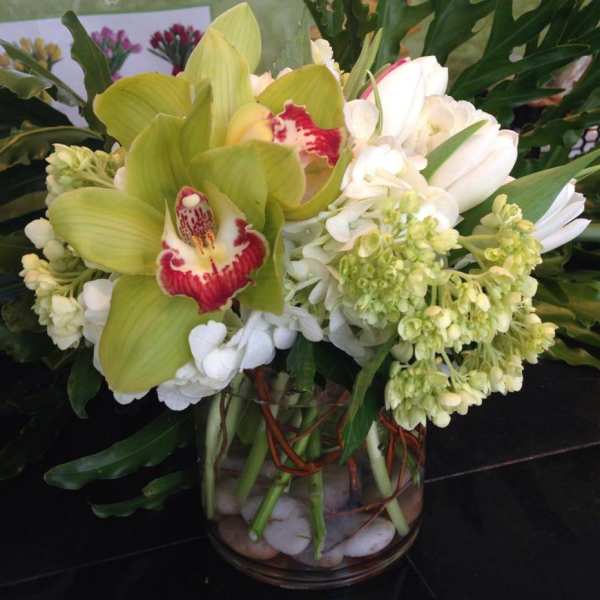 Green and white orchid arrangement in a glass vase