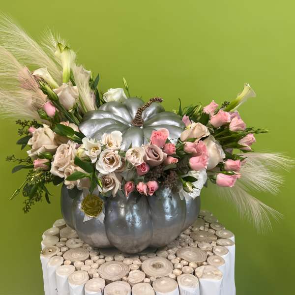 Pink and white flowers arranged in a silver pumpkin container