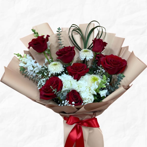 Bouquet of red roses and white flowers wrapped in beige paper with a red ribbon