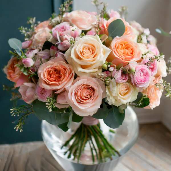 Bouquet of peach and pink roses in a clear glass vase
