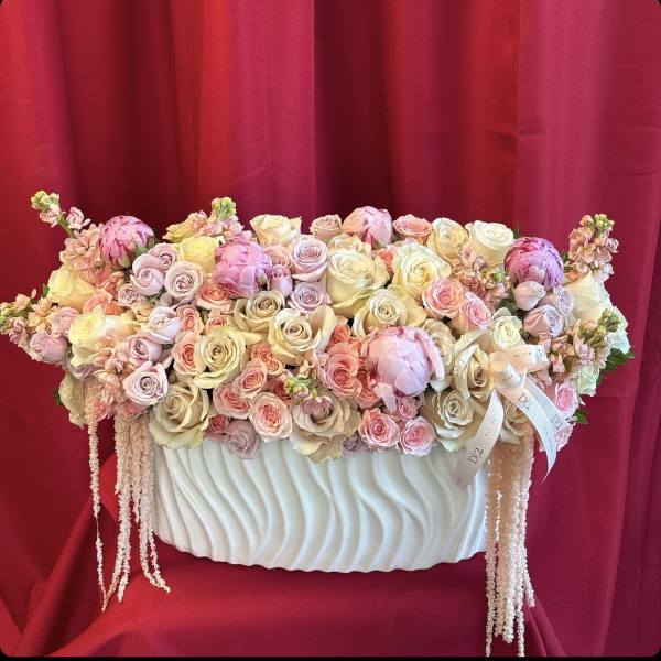 Pastel roses and peonies arranged in a white vase