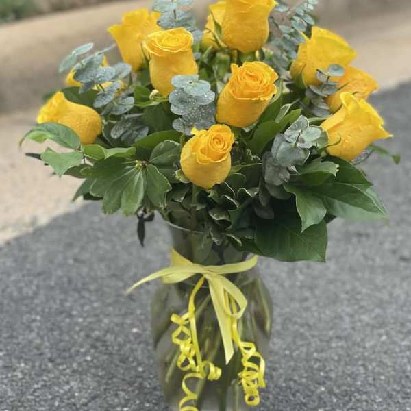 Yellow roses in a glass vase with a yellow ribbon