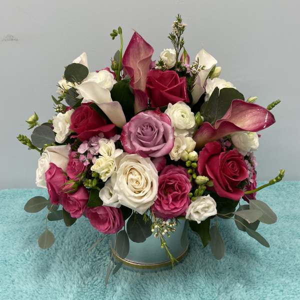 Bouquet of pink and white roses with calla lilies in a round vase
