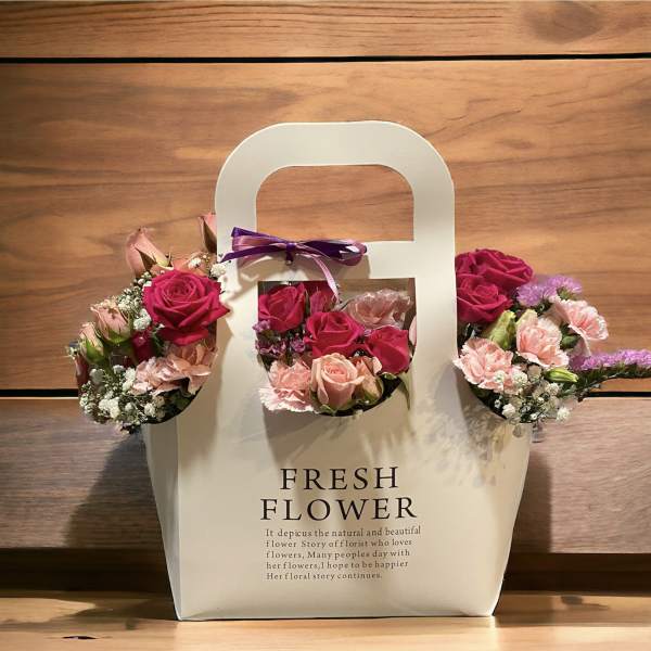Three small rose bouquets attached to a white gift bag