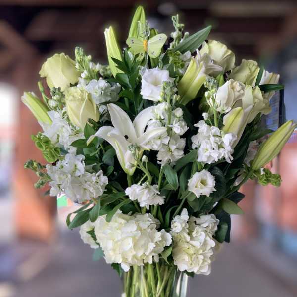 White lilies and pale roses in a tall glass vase