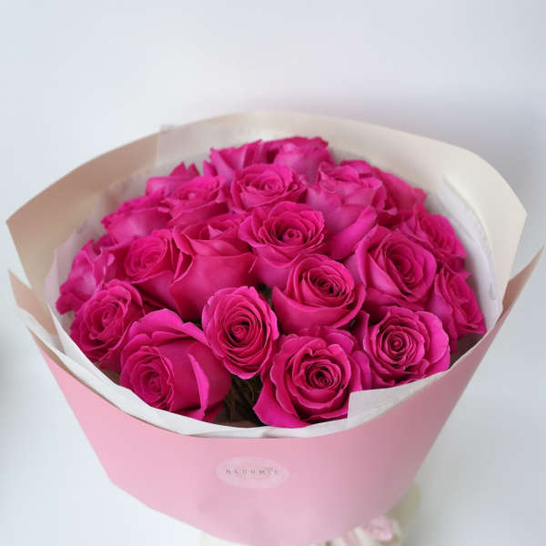 Bouquet of bright pink roses wrapped in pink paper