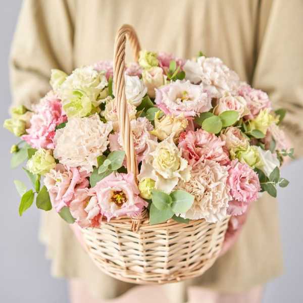Basket of pastel pink and cream flowers with greenery