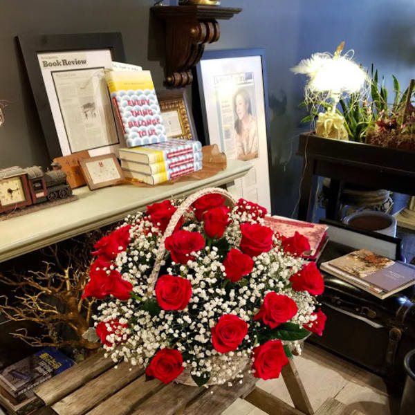Basket of red roses and baby's breath on a wooden table