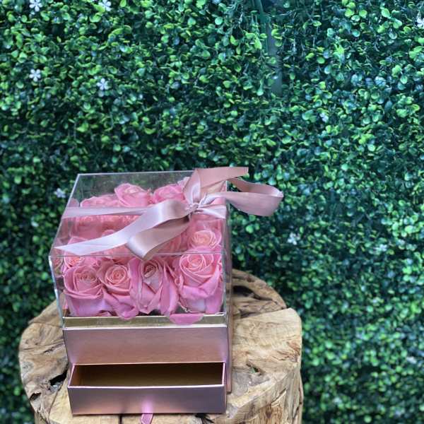 Pink roses in a clear gift box with a ribbon