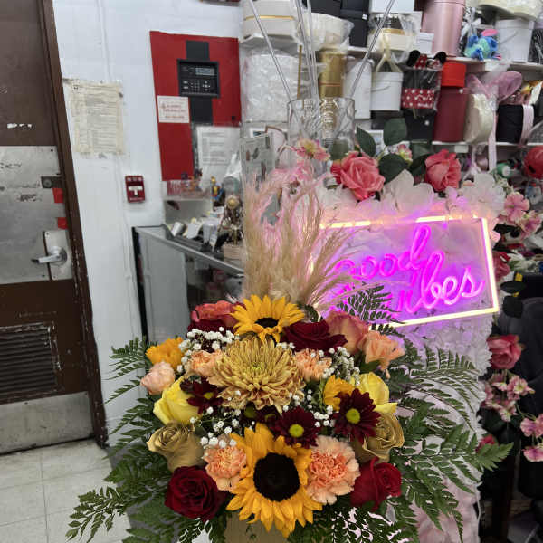 Mixed bouquet with sunflowers, roses, and carnations in a gold vase