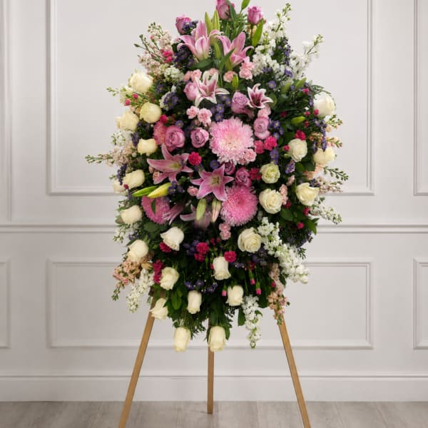 Large standing floral spray with pink, white, and purple flowers on a wooden easel
