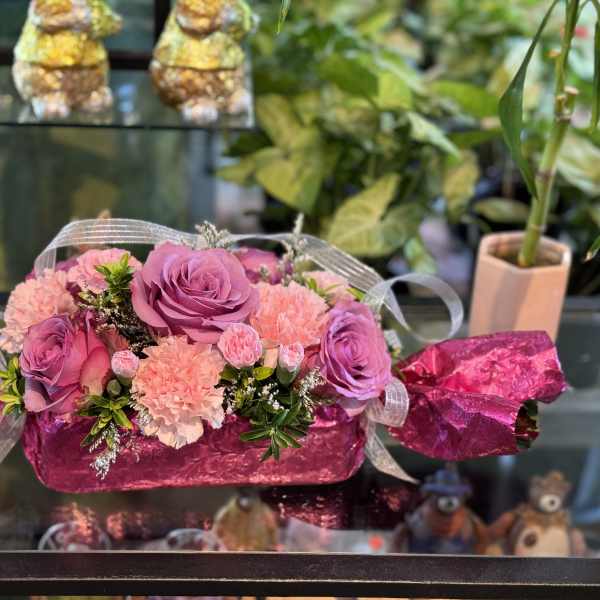Pink and purple roses with carnations in a candy-shaped gift box