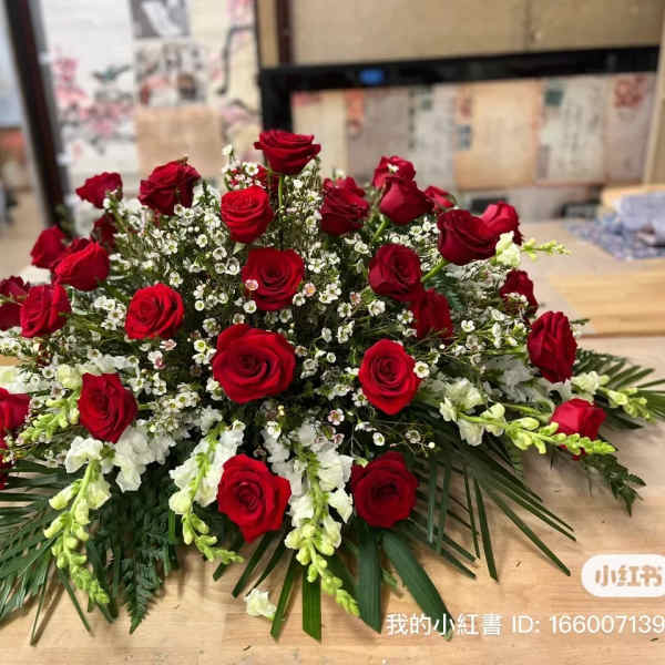 Low arrangement of red roses and white filler flowers on a table
