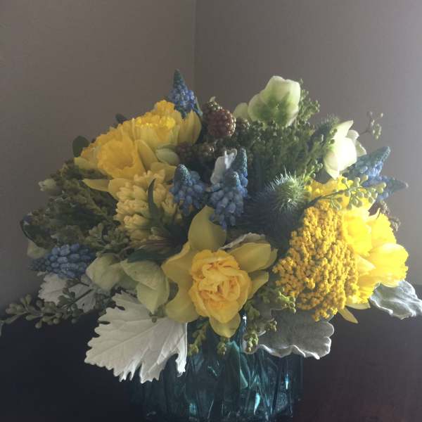 Yellow and blue mixed flower arrangement in a glass vase