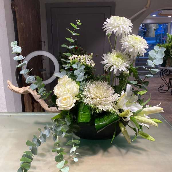 White floral arrangement with roses, lilies, and tall chrysanthemums in a black bowl