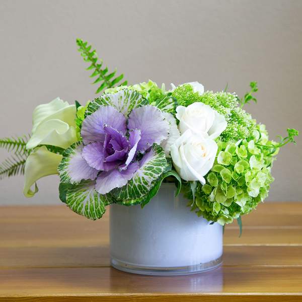 Purple and white flowers arranged in a round glass vase