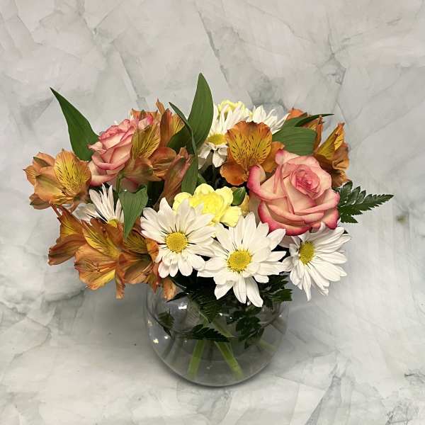 Bouquet of pink roses and white daisies in a round glass vase
