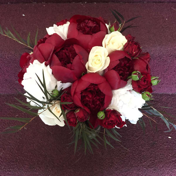 Red and white rose bouquet with dark foliage on a purple carpet