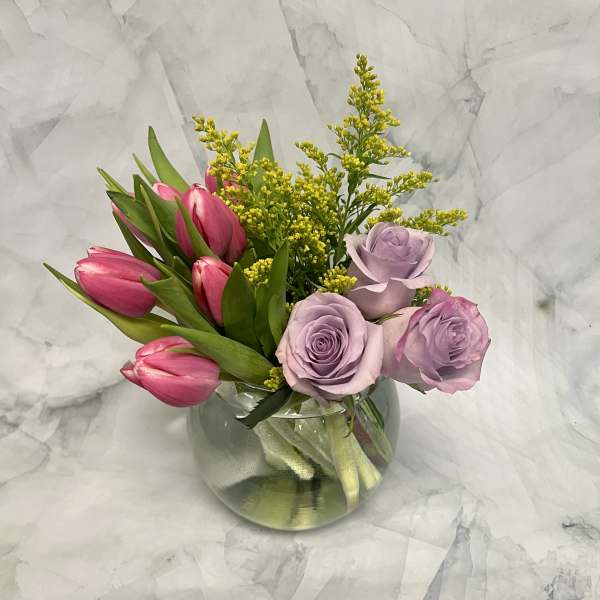 Pink tulips and lavender roses in a clear glass vase