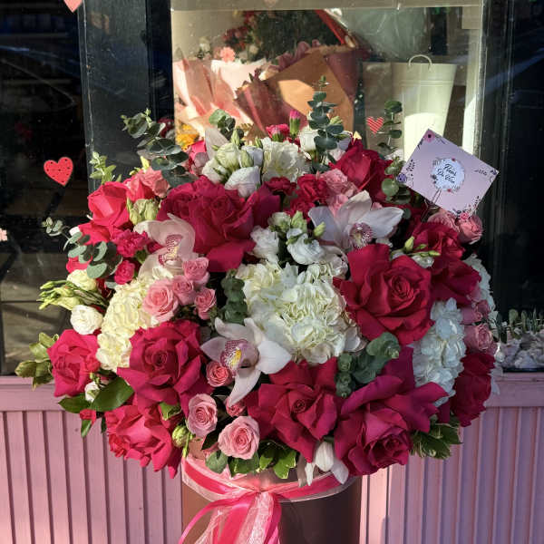Large bouquet of pink and white roses with orchids in a hatbox