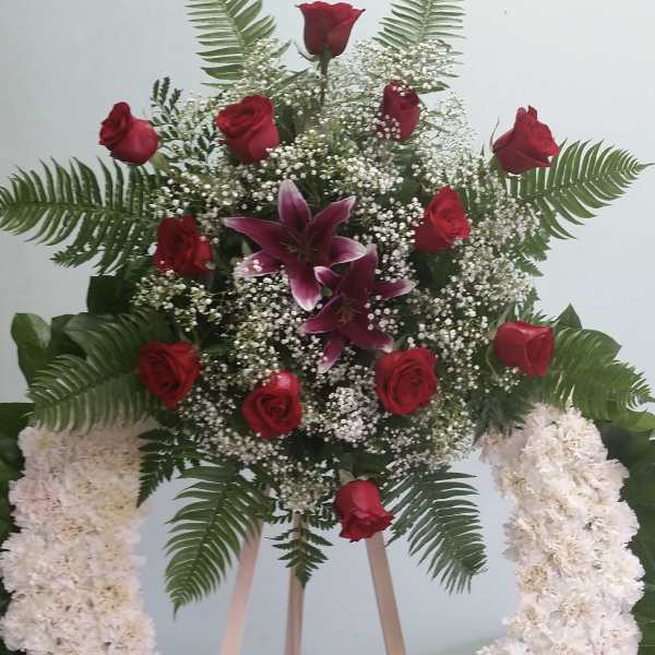 Standing floral wreath with red roses, lilies, and white flowers
