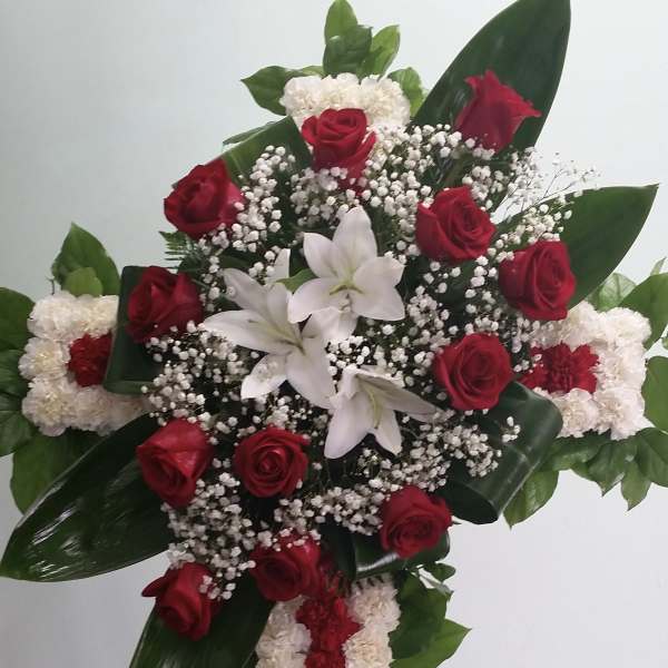 Standing floral spray with red roses, white lilies, and a red-and-white carnation cross