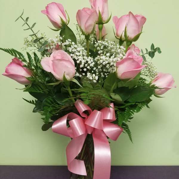 Pink roses in a glass vase with baby's breath and a pink ribbon