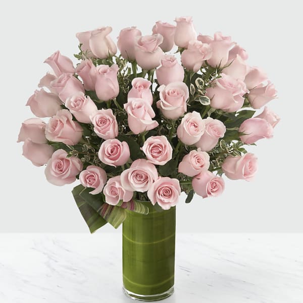 Bouquet of pale pink roses in a tall green glass vase