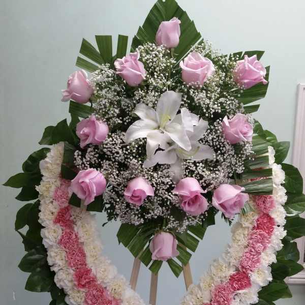 Standing floral wreath with pink roses, white lilies, and a pink-and-white garland
