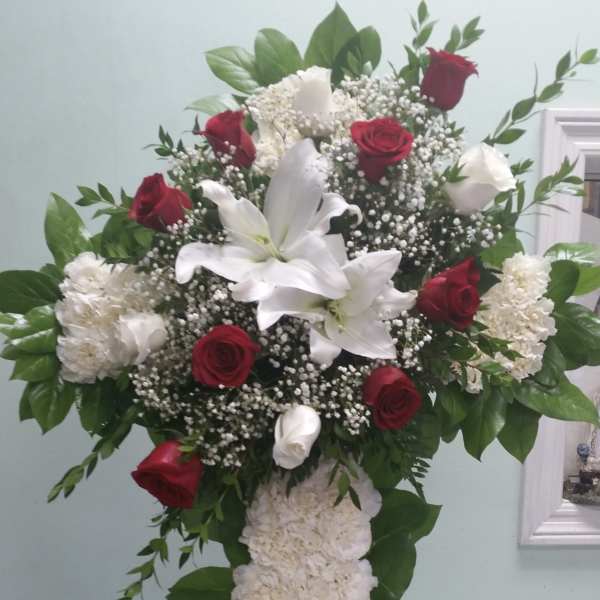 Standing floral cross with red roses, white lilies, and white carnations