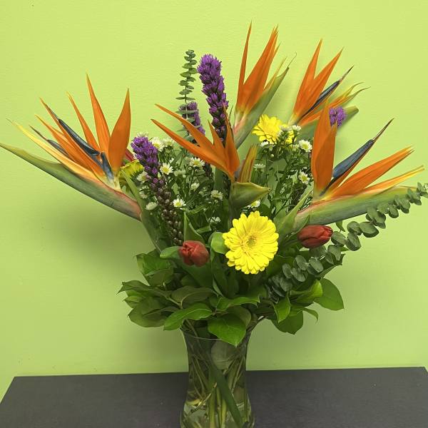 Bouquet of orange bird of paradise and mixed flowers in a glass vase