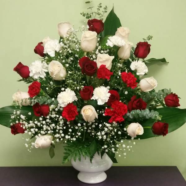 Red and white roses with carnations in a white vase