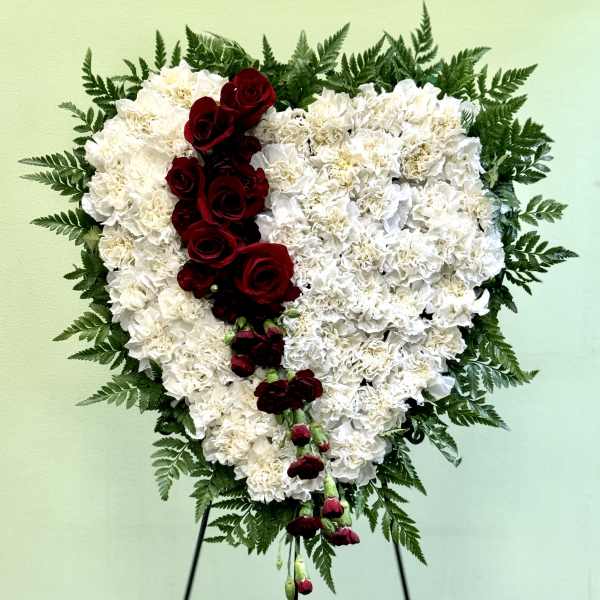 Heart-shaped white floral arrangement with red roses on a stand
