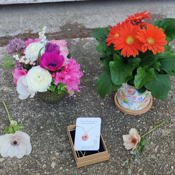Two flower arrangements and a necklace gift box on pavement.