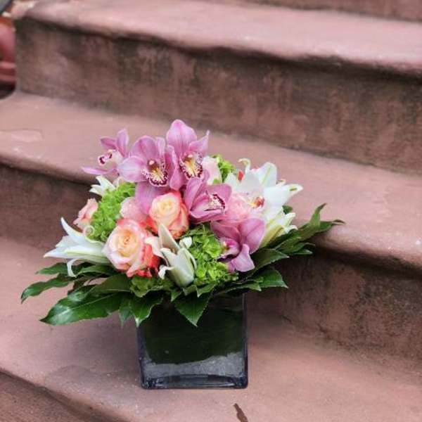 Pink and white floral arrangement in a square glass vase