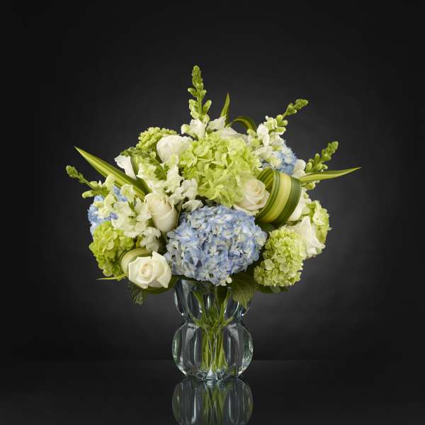 Blue and white floral arrangement in a clear glass vase