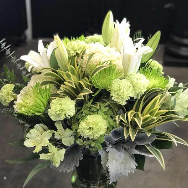 White lilies and green carnations in a glass vase