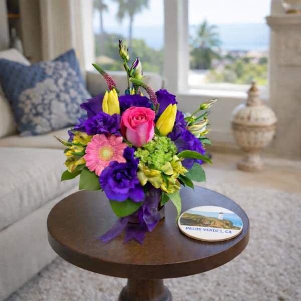Colorful bouquet with a pink rose, purple blooms, and yellow flowers in a vase
