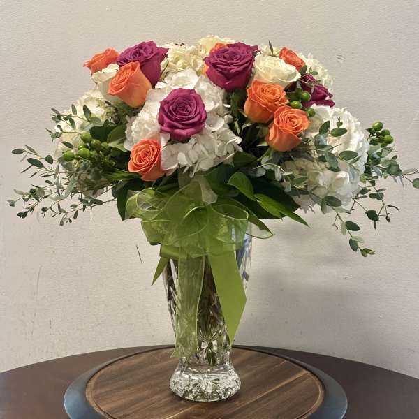 Bouquet of orange and magenta roses in a clear glass vase