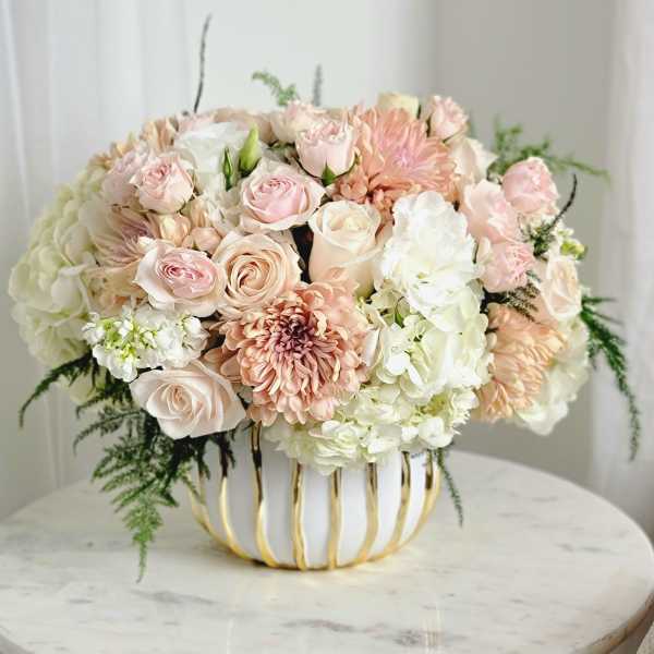 Blush and white floral arrangement in a gold-trimmed vase