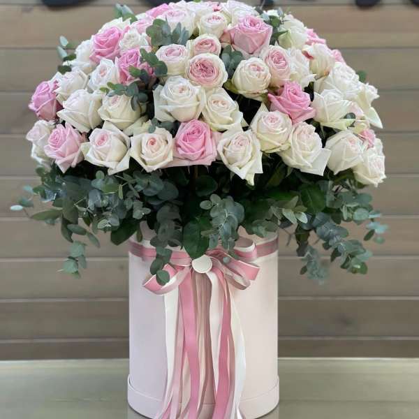 Pink and white roses in a round hatbox with ribbon streamers
