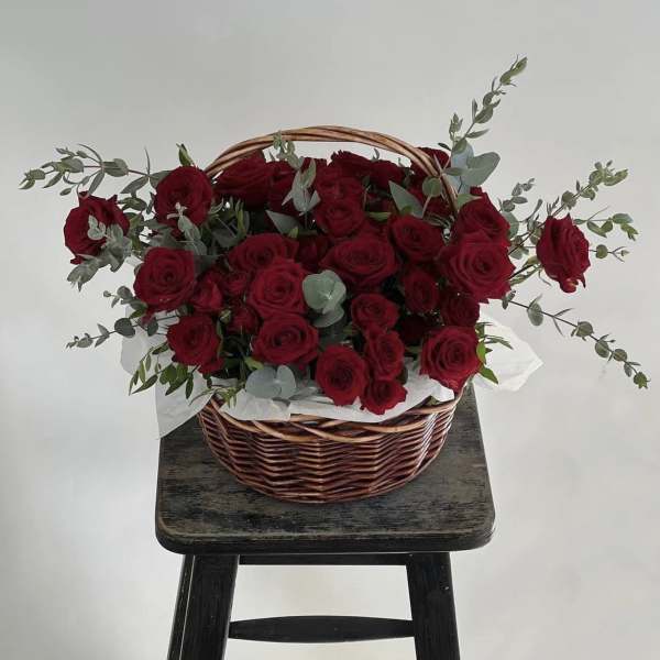 Basket of red roses with eucalyptus on a stool