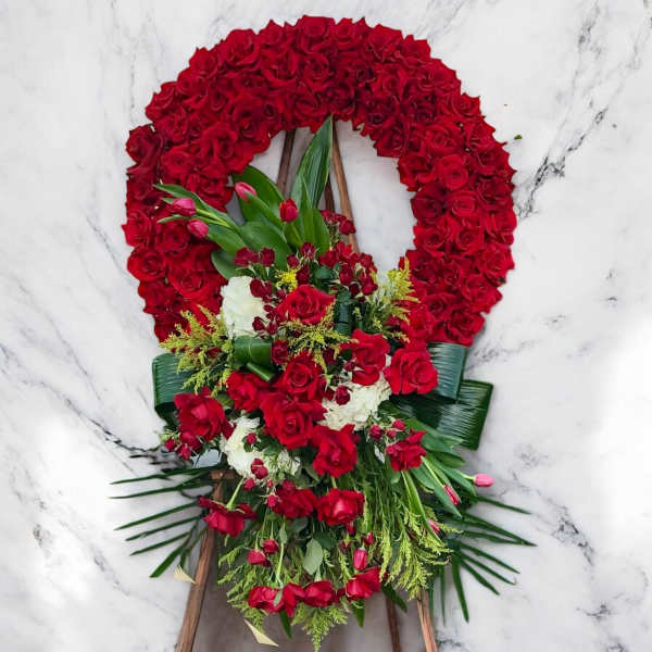 Red rose funeral wreath with a cascading floral spray on an easel