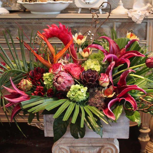 Tropical floral arrangement with pink lilies and protea in a rectangular container