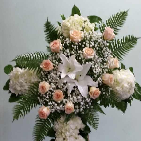 Standing floral cross with white blooms, peach roses, and fern fronds