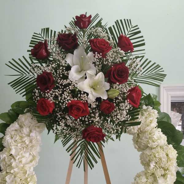 Standing floral wreath with red roses, white lilies, and white hydrangeas
