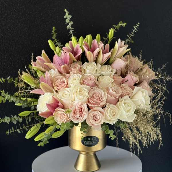 Pink and white roses with lilies in a gold vase